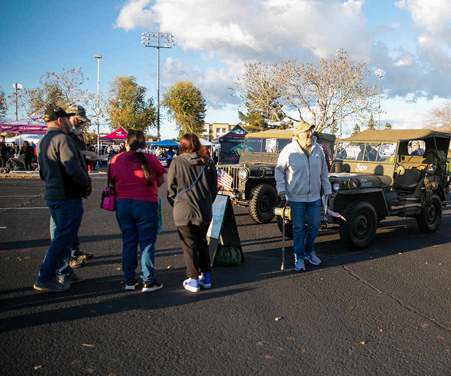 a group of people standing in a parking lot with army jeeps