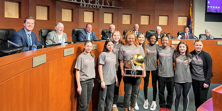 The Valley Vista High School girls basketball team holding their trophy and posing for a picture in the council chambers.