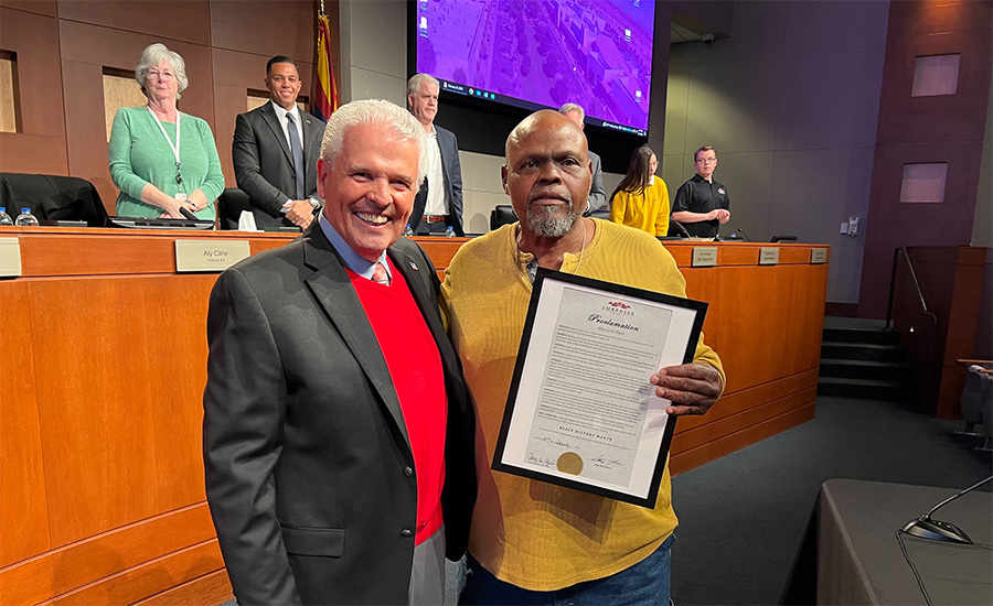 Tim Williams holding the proclamation and standing next to Mayor Hall.